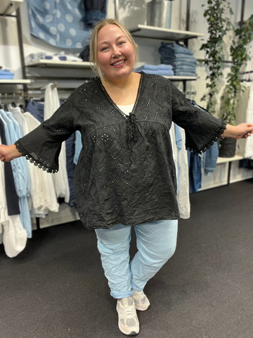 Plus size tunikaen "Anni" fra Sigensgaard har en rigtig god facon, som gør at de fleste plus size piger vil blive glad for den. Den er med trompet-ærmer, v-hals og smukke broderingsdetaljer. Her ses den i sort.