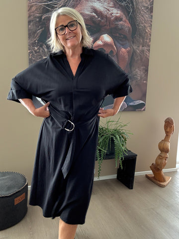 Smart plus size kjole med bælte der definerer taljen. Den er med v-hals, korte ærmer og krave. Fås fra en str. 42 til og med str. 54.