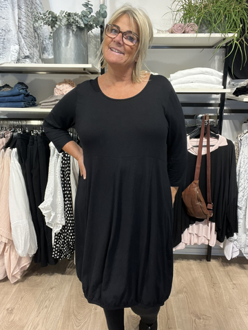 Hilda er plus size kjolen, som du vil elske. Modellen har en fin ballon-effekt, som er perfekt til de fleste plus size kvinder. Kvaliteten er en lækker viskose. Derudover har den 3/4 ærmer og rund hals. Her ses den i sort.