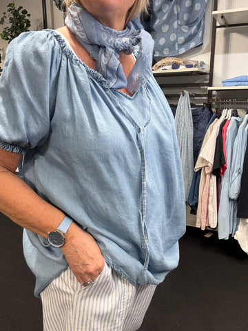Plus size bluse i en blød tencel kvalitet med denim look. Den har en blød v-hals, som kan åbnes og lukkes med snøre. Derudover er der elastik ved ærme og halsåbning.