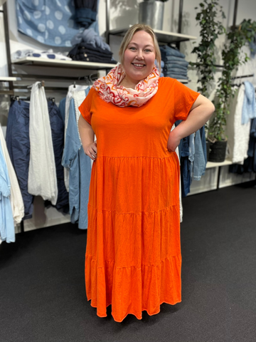 Lækker og lang bomuldskjole som er perfekt til plus size kvinden som leder efter en kjole der er alsidig. Den er fantastisk året rundt, men specielt i foråret og sommeren. Her ses den i orange.