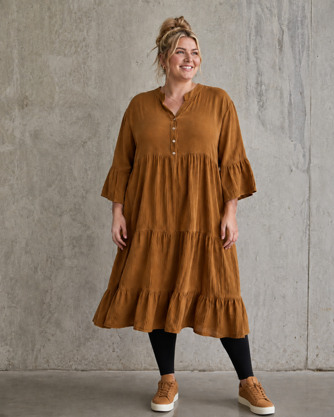 Ella plus size kjole i mørk marineblå med V-hals, knapper, 3/4 ærmer og flot vidde – stylet med sorte leggings og karamel sneakers.
Billed er ai generet