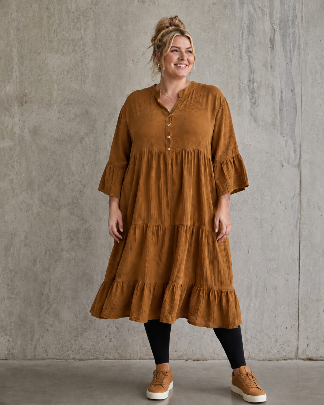Ella plus size kjole i mørk marineblå med V-hals, knapper, 3/4 ærmer og flot vidde – stylet med sorte leggings og karamel sneakers.
Billed er ai generet