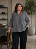 En plus size skjorte med krave, brede 3/4 ærmer. Den har en god længde og går ned og dækker det vi gerne vil ha' dækket. 

Billedet er genereret vha. AI.