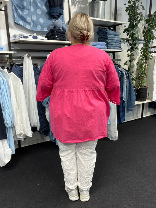 Plus size tunikaen "Anni" fra Sigensgaard har en rigtig god facon, som gør at de fleste plus size piger vil blive glad for den. Den er med trompet-ærmer, v-hals og smukke broderingsdetaljer. Her ses den i pink.