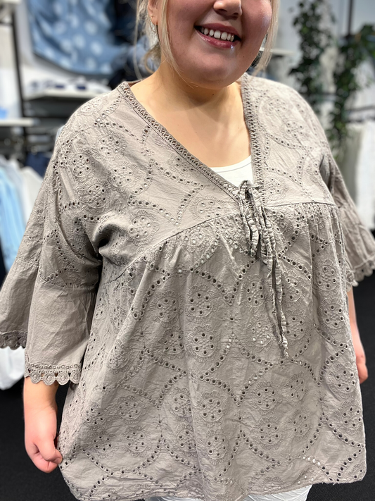 Plus size tunikaen "Anni" fra Sigensgaard har en rigtig god facon, som gør at de fleste plus size piger vil blive glad for den. Den er med trompet-ærmer, v-hals og smukke broderingsdetaljer. Her ses den i farven taupe. 