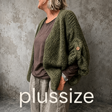 Mona plussize cardigan i chunky strik, stylet i et afslappet look mod en rå, rustik baggrund.
billed er ai generet
