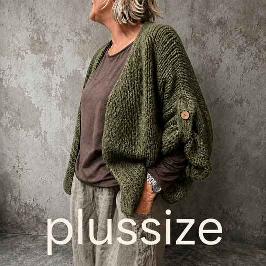 Mona plussize cardigan i chunky strik, stylet i et afslappet look mod en rå, rustik baggrund.
billed er ai generet