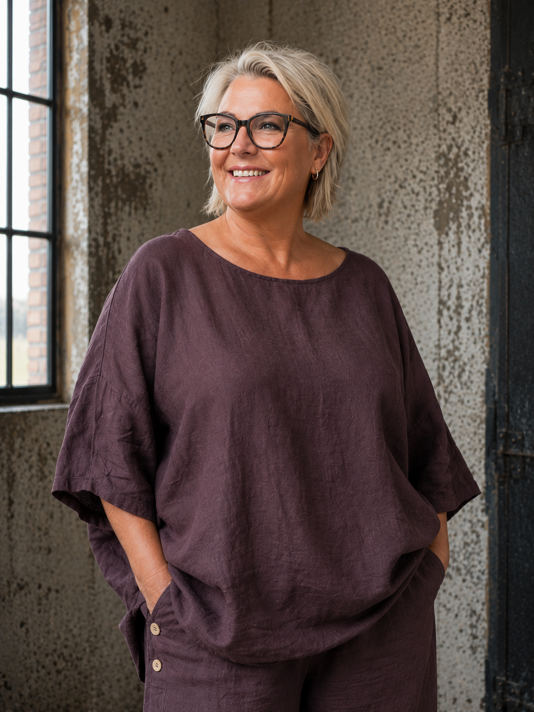**AI-genereret inspirationsbillede af Linda hør tunika. Tunikaen har en løs og rummelig pasform med rund hals, korte ærmer og et flot, enkelt design i 100 % hør. Stylet med jeans på en plus-size model i et råt industrilokale. Fås i mange farver.