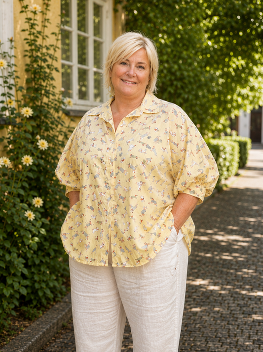 Sød plus size skjorte med hunde på. Den er med 3/4 ærmer og er gennemknappet så den kan bruges både åben og lukket. 

Billedet er genereret vha. AI.