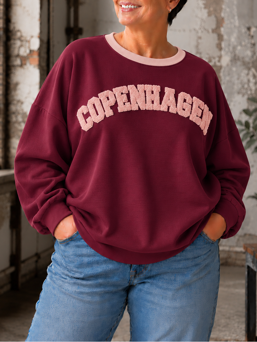 Smart sweatshirt med print foran, hvor der står "Copenhagen". Den er i en smørblød kvalitet som er virkelig dejlig at ha' på - det er en af dem vi bruger til hverdag, men bestemt også til søndagsafslapning. Perfekt til plus size kvinden som ønsker en behagelig sweatshirt. 

Billedet er genereret vha. AI-teknologi.
