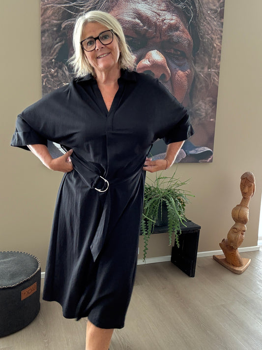 Smart plus size kjole med bælte der definerer taljen. Den er med v-hals, korte ærmer og krave. Fås fra en str. 42 til og med str. 54.