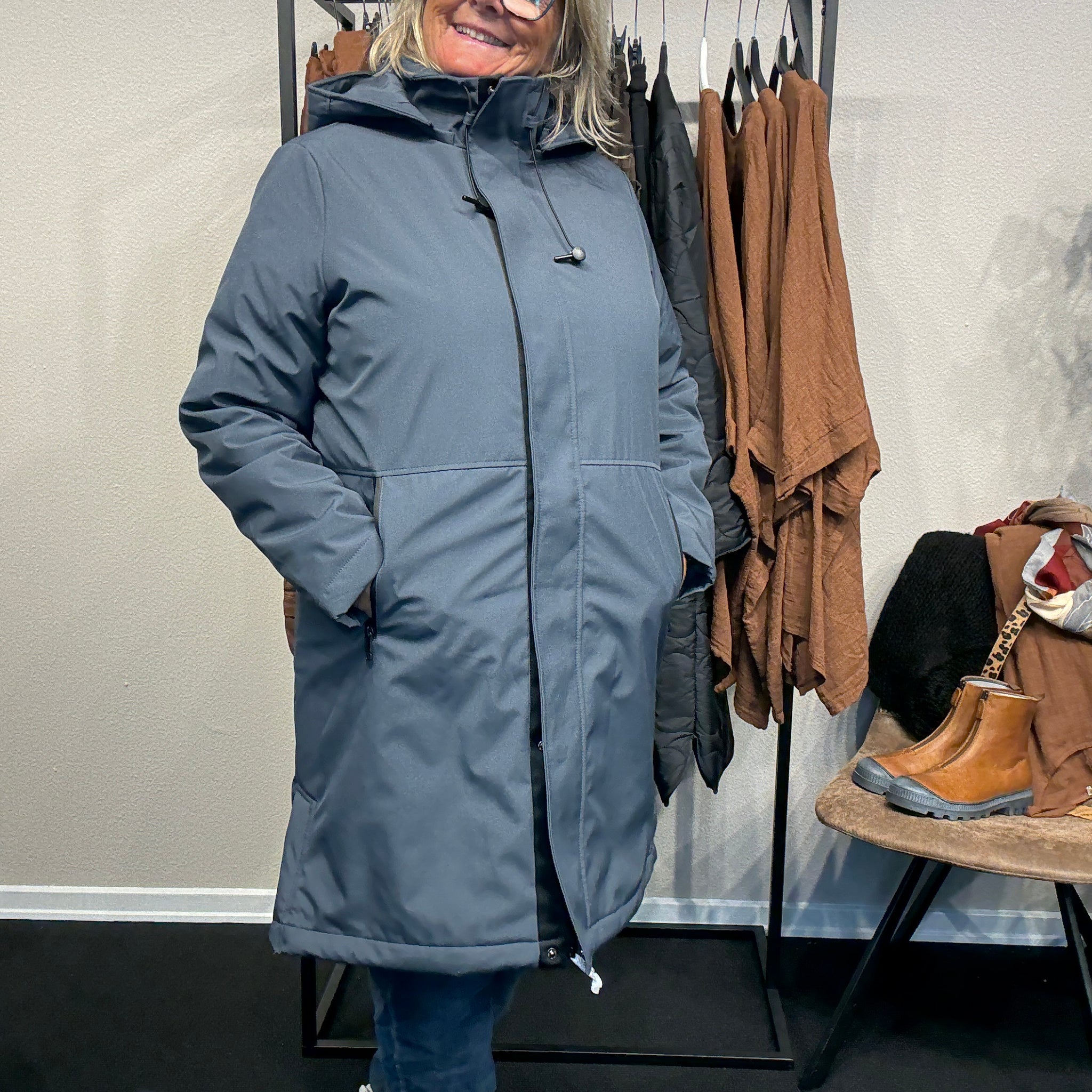 Smart og funktionel plus size jakke efterårs/vinter jakke hvor der er mulighed for at knappe en smule op i siden. Den er med lange ærmer, hætte og så har den lynlås lukning hele vejen ned, samt lommer med lynlås. Rigtig god længde som går til lige under knæet.