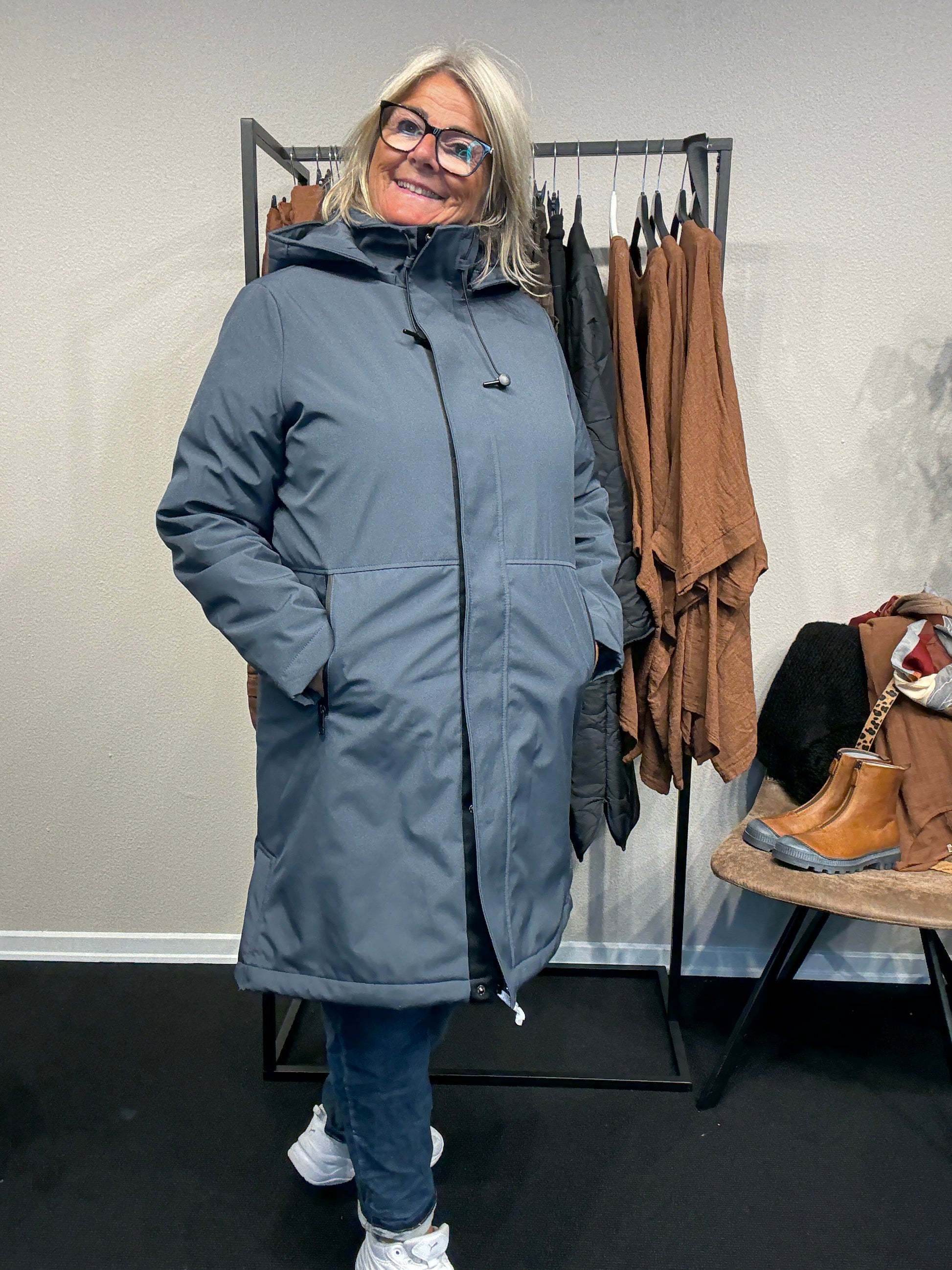 Smart og funktionel plus size jakke efterårs/vinter jakke hvor der er mulighed for at knappe en smule op i siden. Den er med lange ærmer, hætte og så har den lynlås lukning hele vejen ned, samt lommer med lynlås. Rigtig god længde som går til lige under knæet.