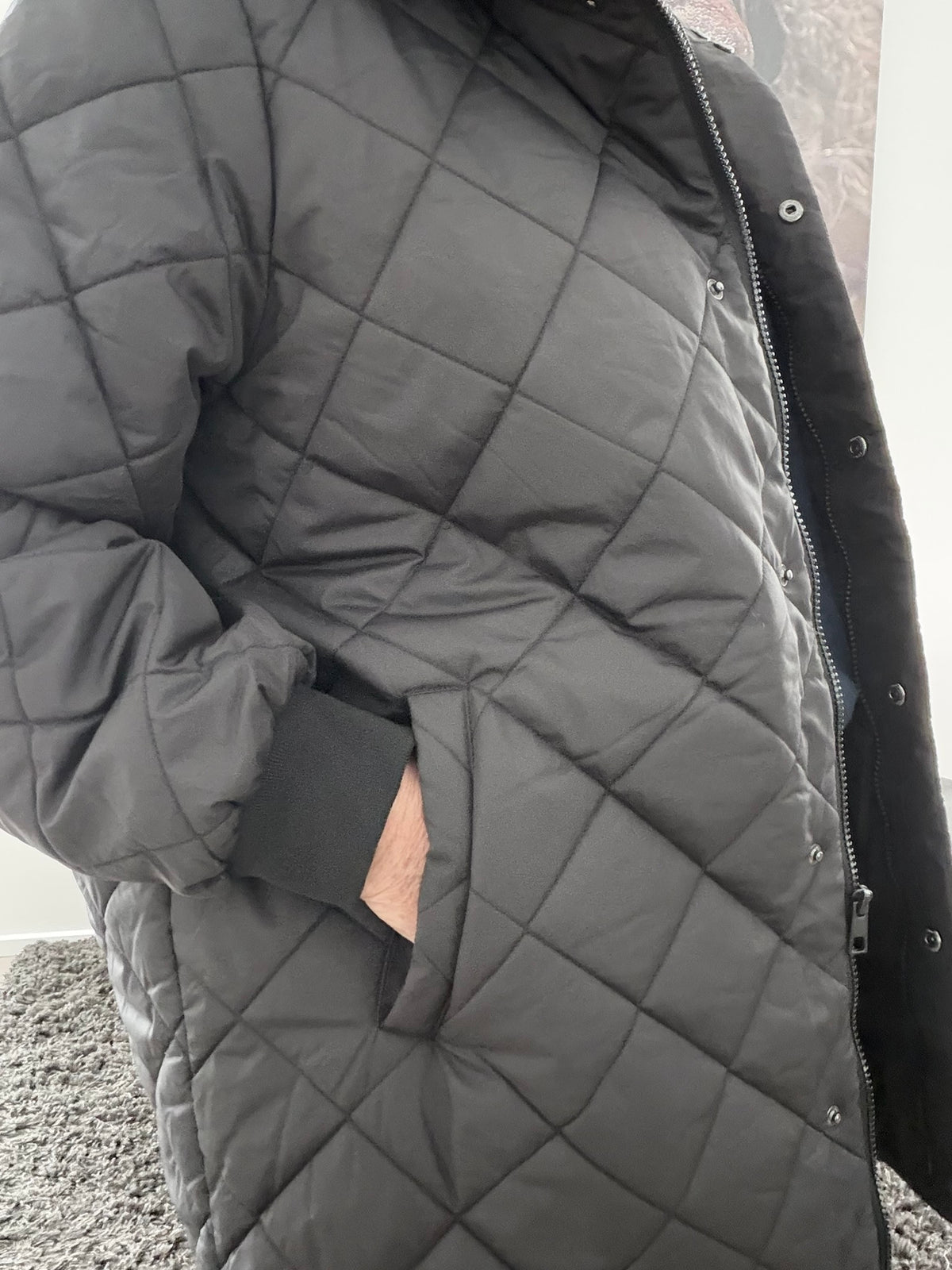 CarJuliet plussize quiltjakke i sort med flot quiltet mønster, høj krave og praktiske sidelommer. Rummelig pasform til plus size. Billedet er AI-genereret.