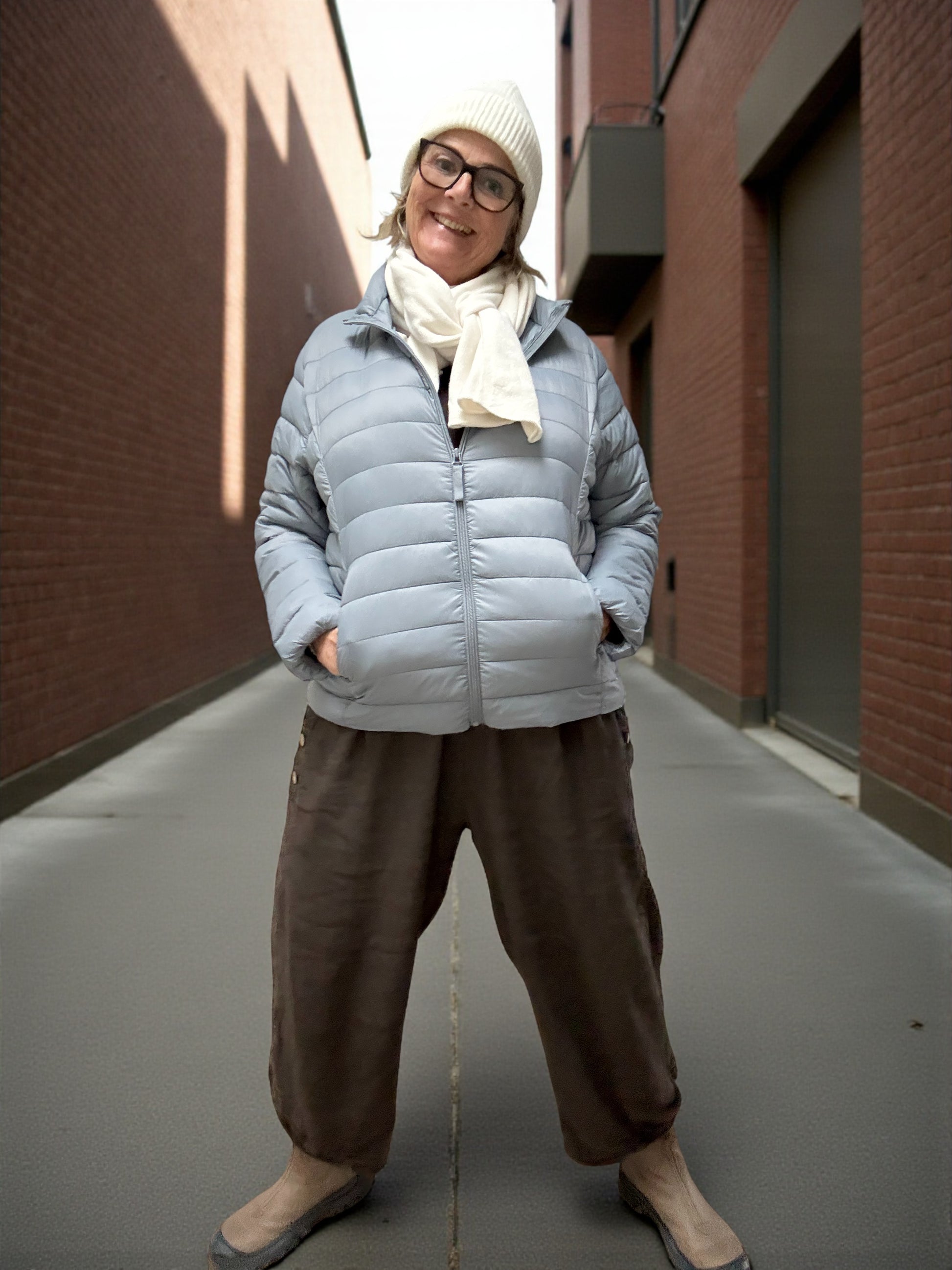 Jakken har høj hals, lange ærmer, lynlås foran og praktiske sidelommer med lynlås. Den er let foret med blød, syntetisk fyld, som giver god varme uden at virke tung.