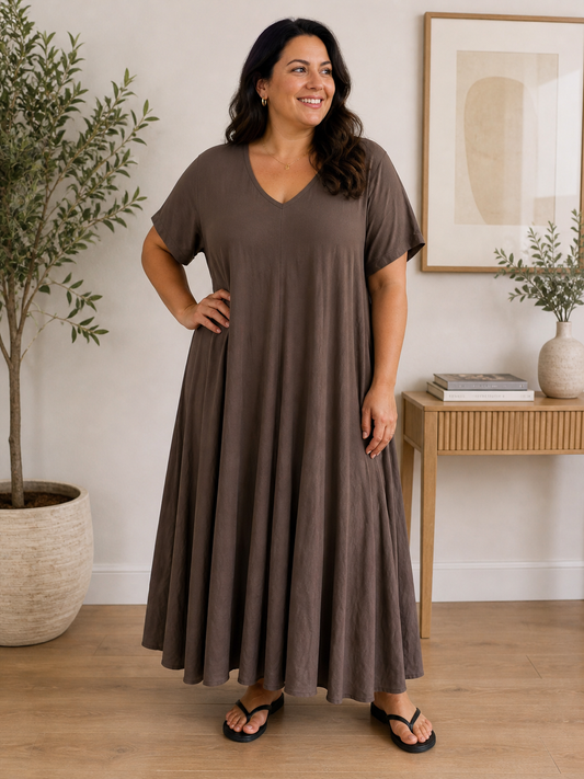 “Pernille plussize viskose kjole i smuk A-facon. Modellen er 168 cm høj og bruger størrelse 46/48. Kjolen har korte ærmer, V-udskæring og et løstsiddende, flatterende fald i en varm camel farve.”billed er Ai generet