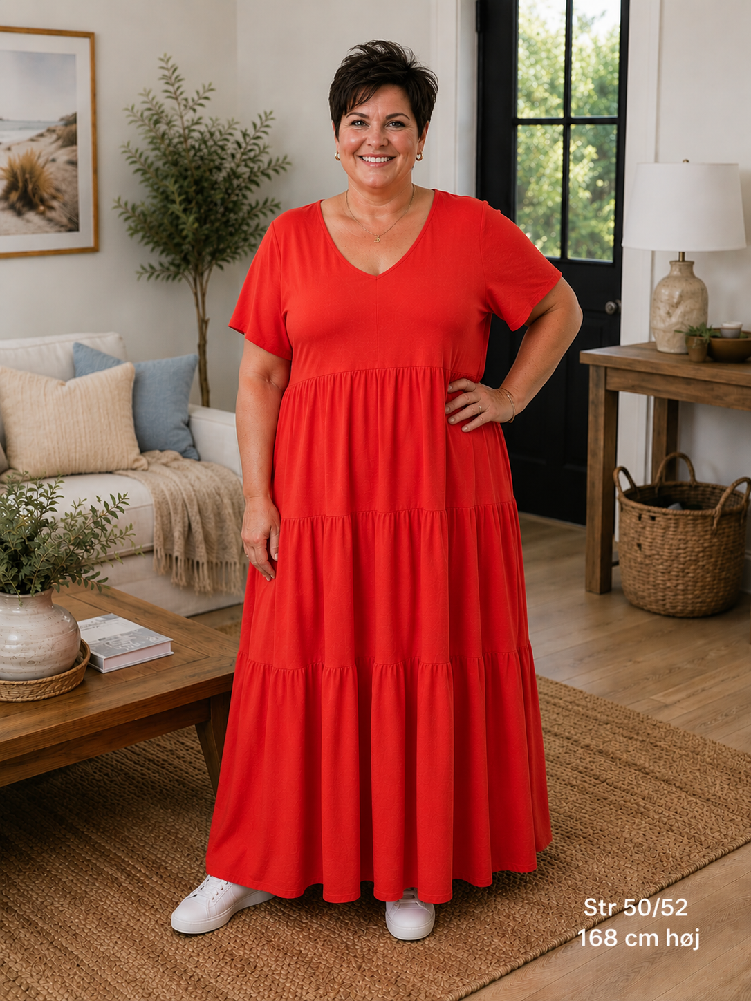 Hanne bomuldskjole i rød – lang plussize kjole med V-hals og korte ærmer. Kjolen har en løs A-facon med smukke flæsepaneler, som giver et flot fald. Vist på model i str. 50/52, 168 cm høj. En komfortabel bomuldskjole til pluskvinder, perfekt til både hverdag og sommerens hyggelige stunder.