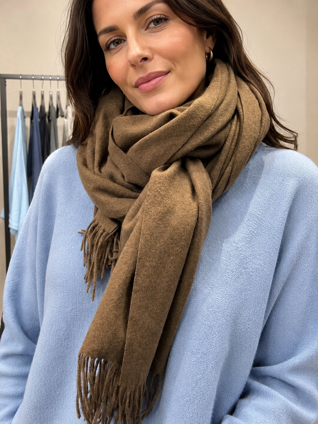 Blødt og lækkert pashmina tørklæde i lysegrå med fine frynser. Tørklædet føles dejligt blødt mod huden og kradser ikke. Perfekt til både hverdag og fest. Et skønt tørklæde, du vil elske at svøbe dig i. Billedet er AI-genereret.