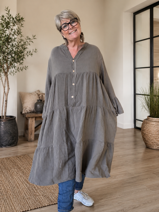 Ella plus size kjole i mørk marineblå med V-hals, knapper, 3/4 ærmer og flot vidde – stylet med sorte leggings og karamel sneakers.
Billed er ai generet