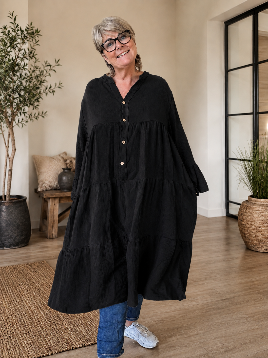 Ella plus size kjole i mørk marineblå med V-hals, knapper, 3/4 ærmer og flot vidde – stylet med sorte leggings og karamel sneakers.
Billed er ai generet