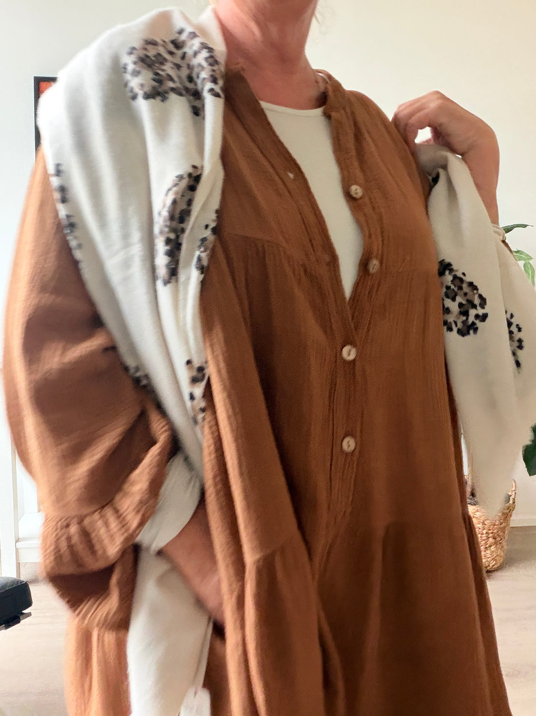 Ella plus size kjole i karamel med V-hals, knapper, 3/4 ærmer og flot vidde – stylet med jeans og sneakers.

Billedet er ai genereret