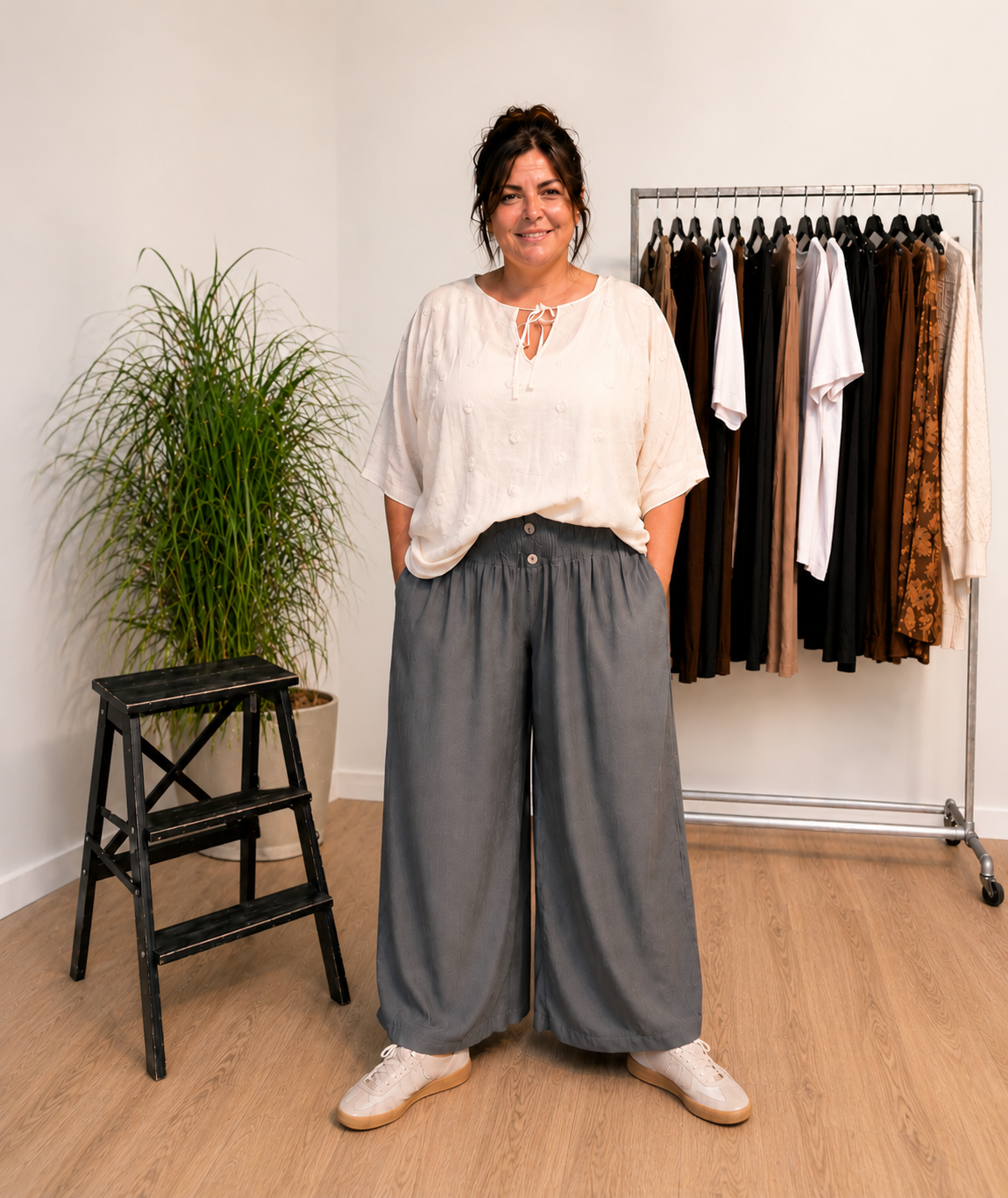 "Model i Tora viddebuks med bred smock-elastik i taljen, dekorative knapper og vide ben. Buksen vises i Grå sammen med en løs beige bluse. Modellen er str. 46/48 og 168 cm høj." Billed er ændret i Ai