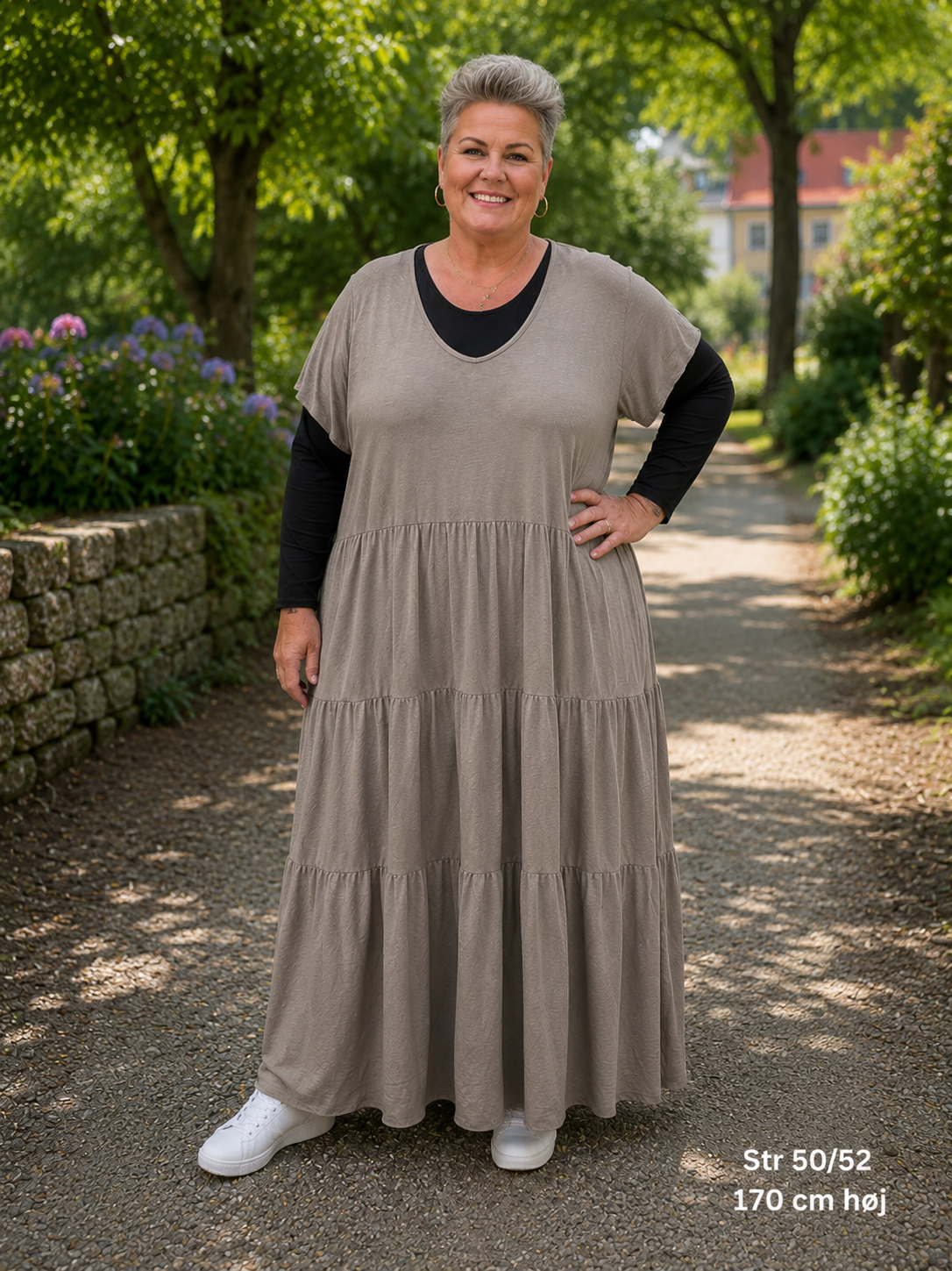 Hanne bomuldskjole i rød – lang plussize kjole med V-hals og korte ærmer. Kjolen har en løs A-facon med smukke flæsepaneler, som giver et flot fald. Vist på model i str. 50/52, 168 cm høj. En komfortabel bomuldskjole til pluskvinder, perfekt til både hverdag og sommerens hyggelige stunder.
