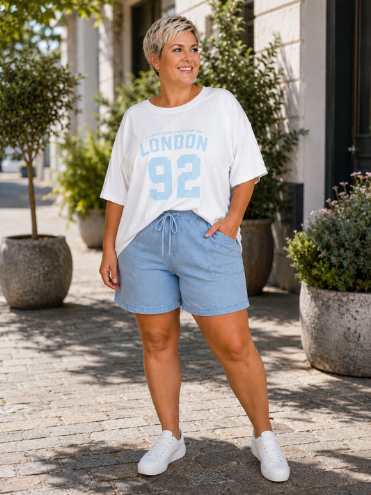 London T-shirt er en afslappet og moderne oversize T-shirt i blød bomuld, designet til plus size kvinder. Modellen har rund hals, korte ærmer og et cool "London 92"-print på brystet, som giver et sporty og trendy look. Den løse pasform gør T-shirten utrolig behagelig at have på og nem at style med jeans, shorts, leggings eller hørbukser. Fås i flere flotte sommerfarver og er perfekt til både hverdag, ferie og afslappede sommerdage.billed er ai generet