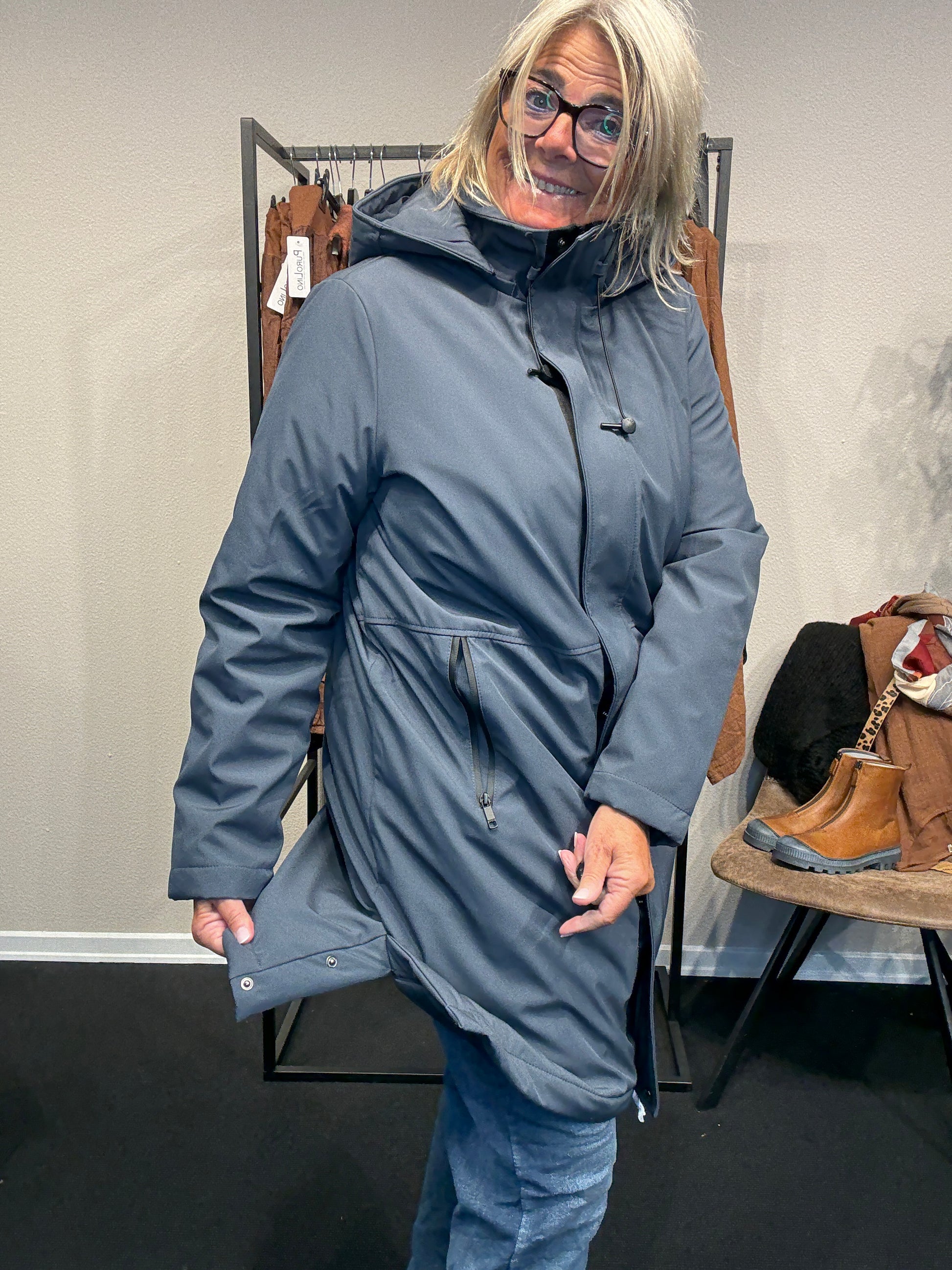 Smart og funktionel plus size jakke efterårs/vinter jakke hvor der er mulighed for at knappe en smule op i siden. Den er med lange ærmer, hætte og så har den lynlås lukning hele vejen ned, samt lommer med lynlås. Rigtig god længde som går til lige under knæet.