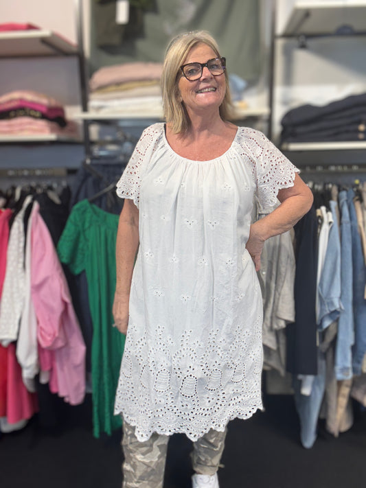Sød og sommerlig kjole med broderingsdetaljer. Den har elastik i halsen, og er med korte ærmer. Den er i 100% bomuld. Her ses den i farven hvid.