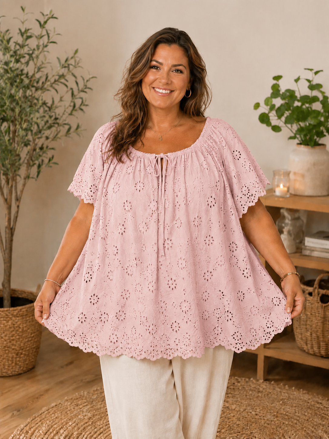 Janne blondebluse i taupe med smukke broderie anglaise-detaljer. Feminin plus size bluse med løs A-facon, elastisk halsudskæring med bindebånd og korte blondeærmer. Den lette bomuldskvalitet giver et luftigt og komfortabelt look, perfekt til både shorts, jeans og hørbukser på varme sommerdage. smart plussize overdel,billed er  ai generet.