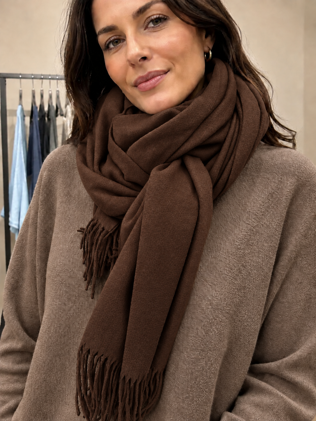 Blødt og lækkert pashmina tørklæde i lysegrå med fine frynser. Tørklædet føles dejligt blødt mod huden og kradser ikke. Perfekt til både hverdag og fest. Et skønt tørklæde, du vil elske at svøbe dig i. Billedet er AI-genereret.