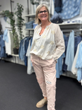 Smuk plus size bluse fra Sigensgaard med broderede guld blomster. Den er i 100% bomuld, som gerne må se lidt krøllet ud. Den har v-hals, lange ærmer som kan smøges op grundet knapåbning ved ærmets afslutning. Her ses den i en flot beige farve.