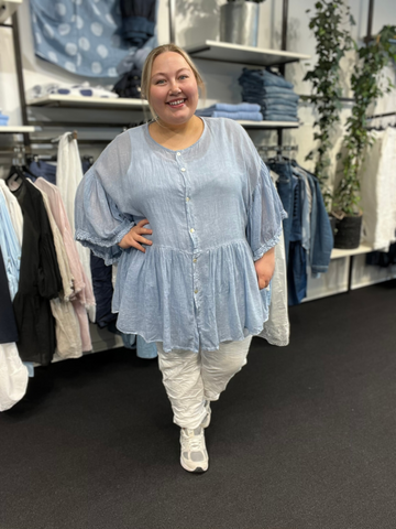 Plus size tunika i en let og tynd bomuld, som er perfekt til de varme dage. Tunikaen er i a-facon, som gør den ideel til plus size kvinder. Den er gennemknappet, så den kan bruges både åben og lukket. Her ses den i farven "lys blå"