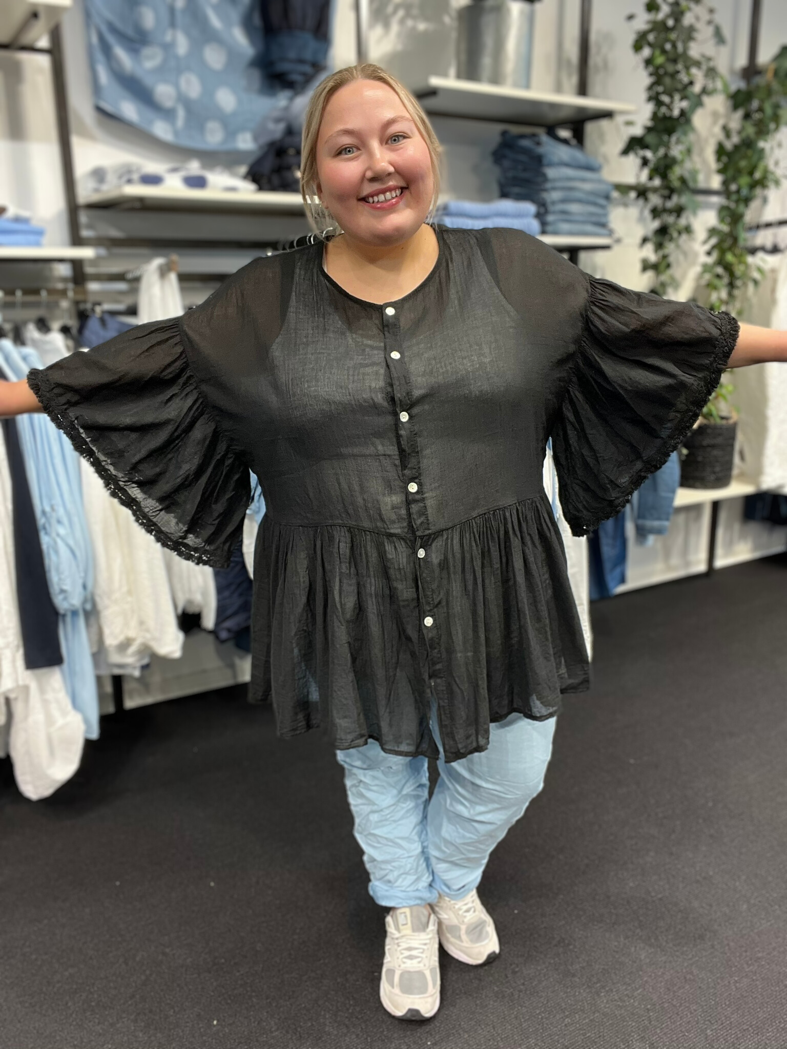Plus size tunika i en let og tynd bomuld, som er perfekt til de varme dage. Tunikaen er i a-facon, som gør den ideel til plus size kvinder. Den er gennemknappet, så den kan bruges både åben og lukket. Her ses den i sort. 