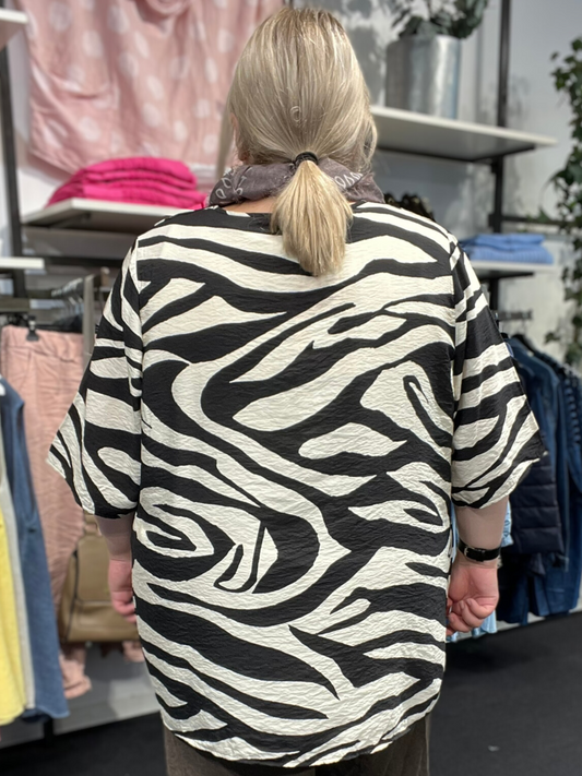 Smart plus size bluse med korte ærmer til den moderigtige plus pige. Den er med korte ærmer og v-hals. Den går fra en str. 42/44 og op til en str. 58.