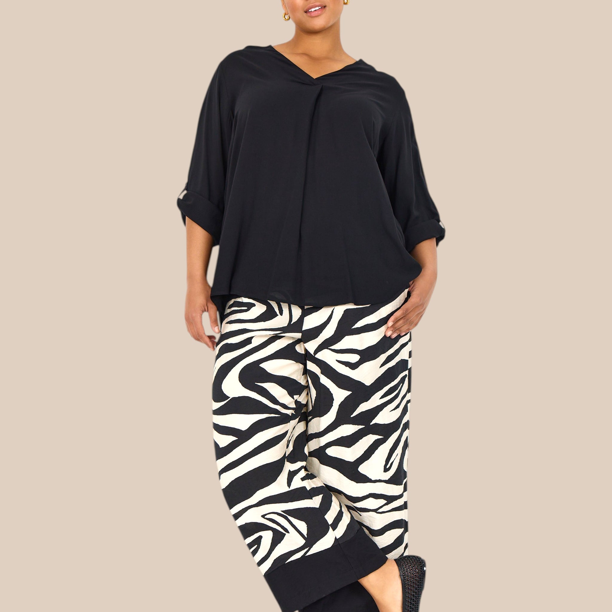 Smart plus size buks i zebra print med brede ben, lommer, elastik i livet og et bredt ensfarvet stykke ved buksens afslutning.