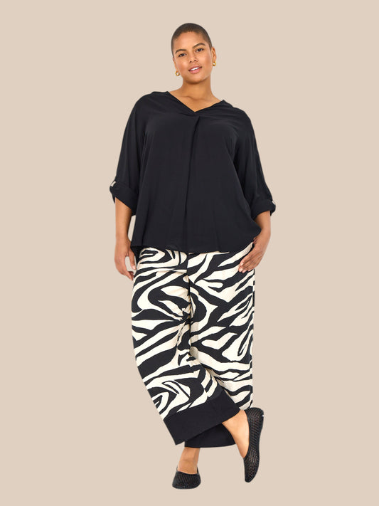 Smart plus size buks i zebra print med brede ben, lommer, elastik i livet og et bredt ensfarvet stykke ved buksens afslutning.