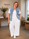 Only Carmakoma jeansvest i klassisk lyseblå denim med flot, figursyet pasform. Vesten har klassisk krave, knaplukning foran og brystlommer med knapper, som giver et moderne og råt udtryk. Den er perfekt over kjoler, T-shirts, tunikaer og bluser og tilfører ethvert outfit et smart lag-på-lag look. En alsidig plus size jeansvest, der er nem at style til både hverdag og fest. billed er ai generet