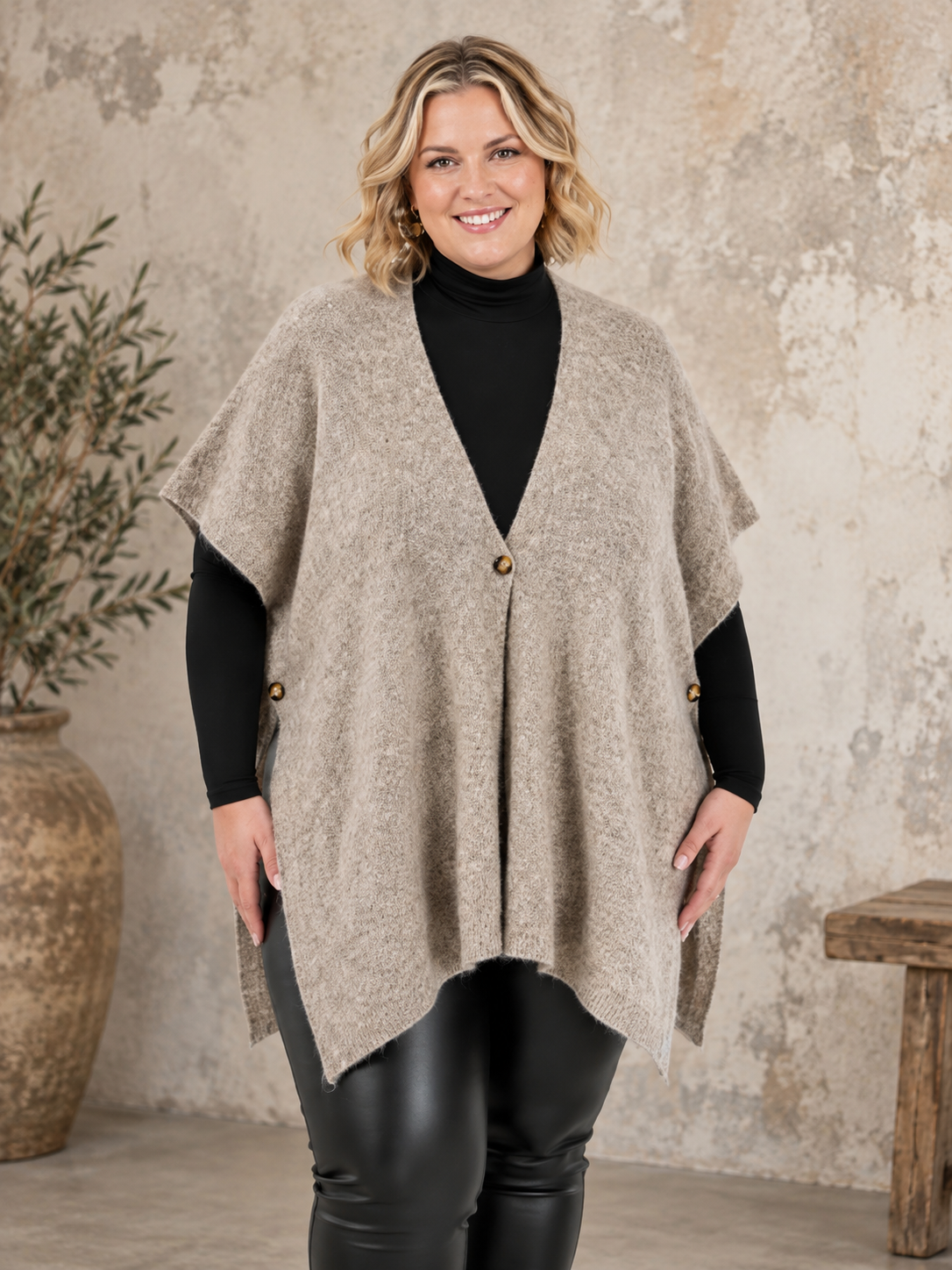 Smart plus size poncho i strik. Den er med flotte knapdetaljer og et perfekt til lag-på-lag looks. 