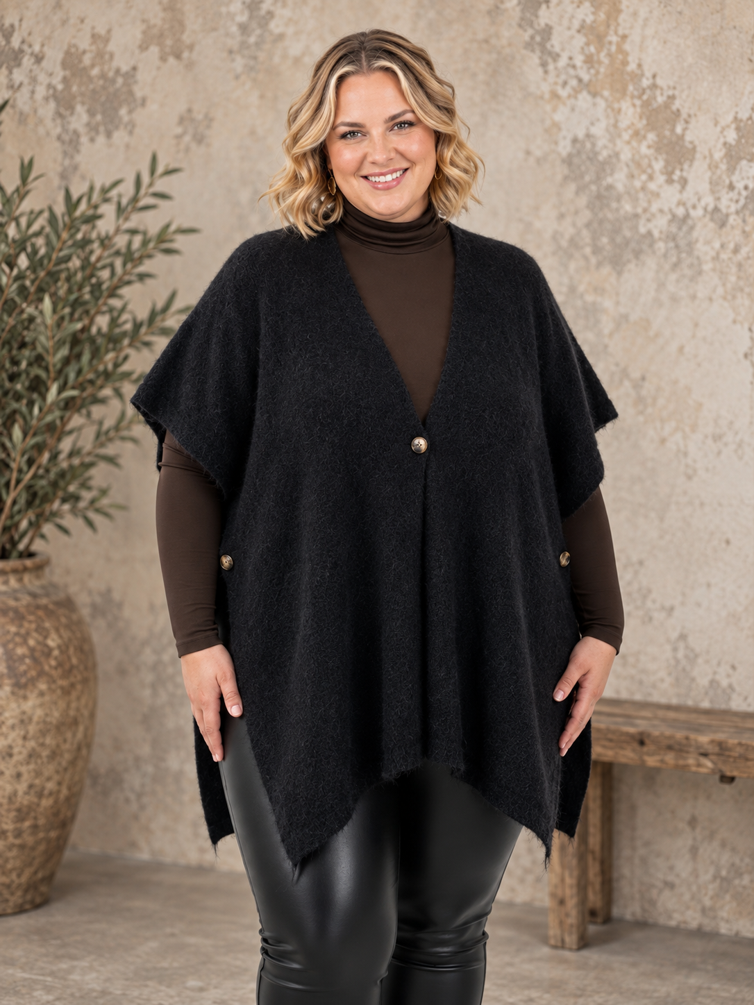 Smart plus size poncho i strik. Den er med flotte knapdetaljer og et perfekt til lag-på-lag looks. 