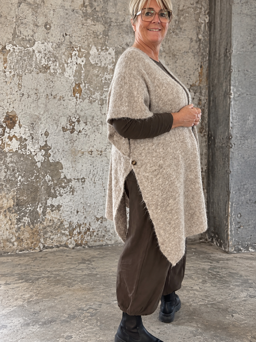 Smart plus size poncho i strik. Den er med flotte knapdetaljer og et perfekt til lag-på-lag looks. 