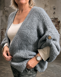 Mona plussize cardigan i chunky strik, stylet i et afslappet look mod en rå, rustik baggrund.
billed er ai generet