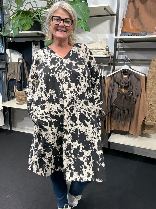 Smart plus size tunika i unikt print. Den er med lange ærmer, v-hals og så er der smock-detalje ved ærmets afslutning. Fra str. 42 til og med str. 58.