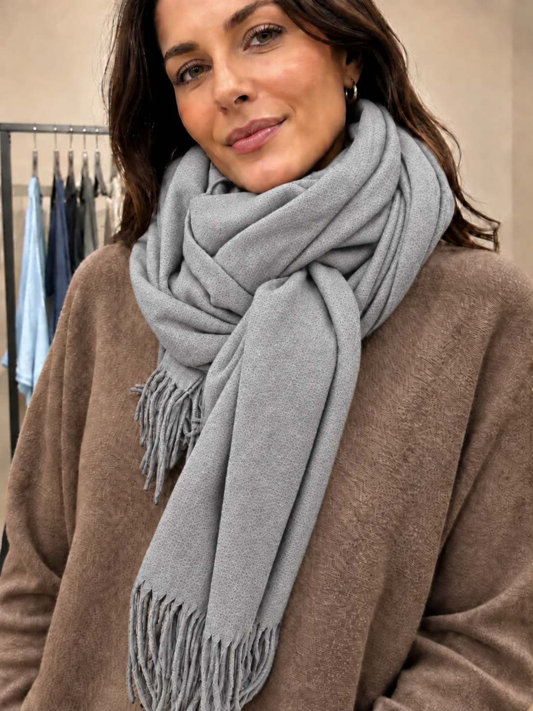 Blødt og lækkert pashmina tørklæde i lysegrå med fine frynser. Tørklædet føles dejligt blødt mod huden og kradser ikke. Perfekt til både hverdag og fest. Et skønt tørklæde, du vil elske at svøbe dig i. Billedet er AI-genereret.