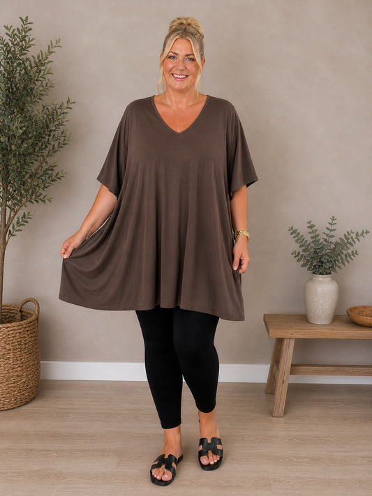 Pernille viskose T-shirt i A-shape med løs og luftig pasform, vist på model der er 168 cm høj og bruger størrelse 46/48. T-shirten er i en mørkebrun nuance og har korte, brede ærmer samt en flatterende V-hals, der giver et afslappet og feminint look. Den falder flot over kroppen og giver god bevægelsesfrihed, hvilket gør den ideel til både hverdag og komfortabel styling.Billed er Ai generet