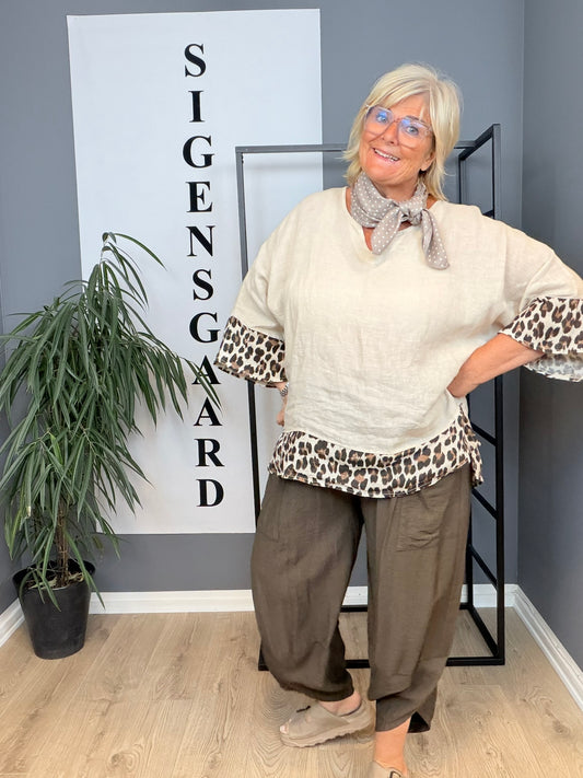 Anna hørtunika i 100 % ren hør, designet til pluspiger med fokus på komfort og pasform. Tunikaen har en løs, luftig silhuet, der falder flot over kroppen, korte eller trekvartærmer og en enkel, tidløs stil. Det naturlige hørstof giver et let og åndbart udtryk, ideelt til varme dage. Fås i rolige, nordiske farver.