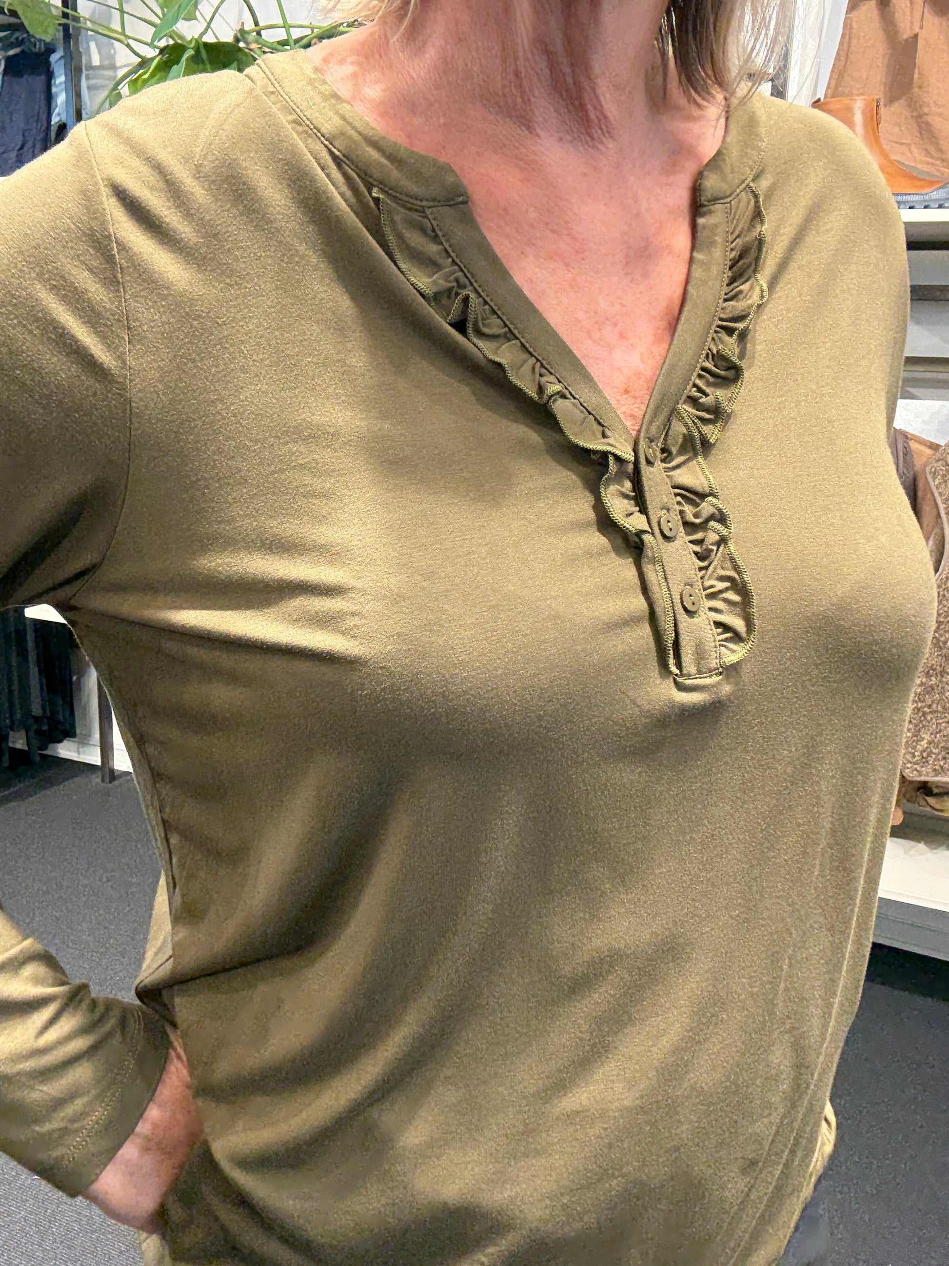 Flot plus size bluse med v-hals og stolpelukning hvor der er påsat flæsekant, som giver et feminint udtryk.kvalitet er jersey så den er blød og lækker