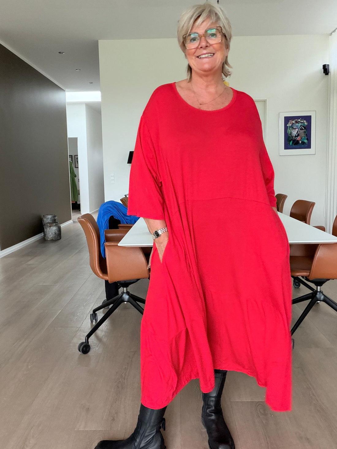 Tulle jersey kjole i plus size med flot, rummelig A-facon, rund hals og løse ærmer. Den bløde jersey falder smukt om kroppen og har et asymmetrisk snit med fine detaljer og god vidde. En smart og behagelig kjole til både hverdag og fest. Billedet er AI-genereret.